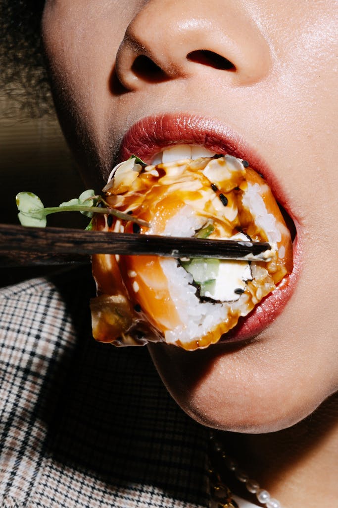 VeganovTrichy Detailed close-up of a person savoring sushi using chopsticks, highlighting culinary culture.