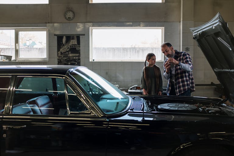 Father explains Car Mechanic Near Me to daughter in an auto repair shop. A moment of learning and bonding.thebaddieshub.com