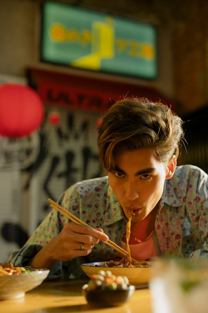 Cha Kee Warrigal Square Man savoring noodles using chopsticks in a traditional Asian restaurant setting.