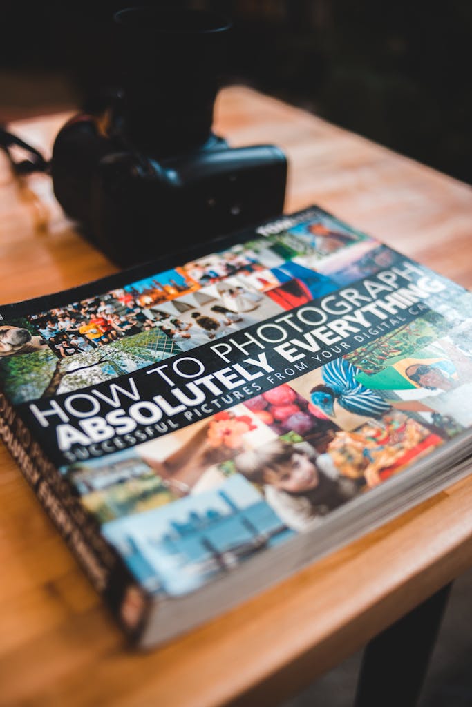 ATF Booru Photography book and DSLR camera on a wooden desk creates a creative workspace vibe.