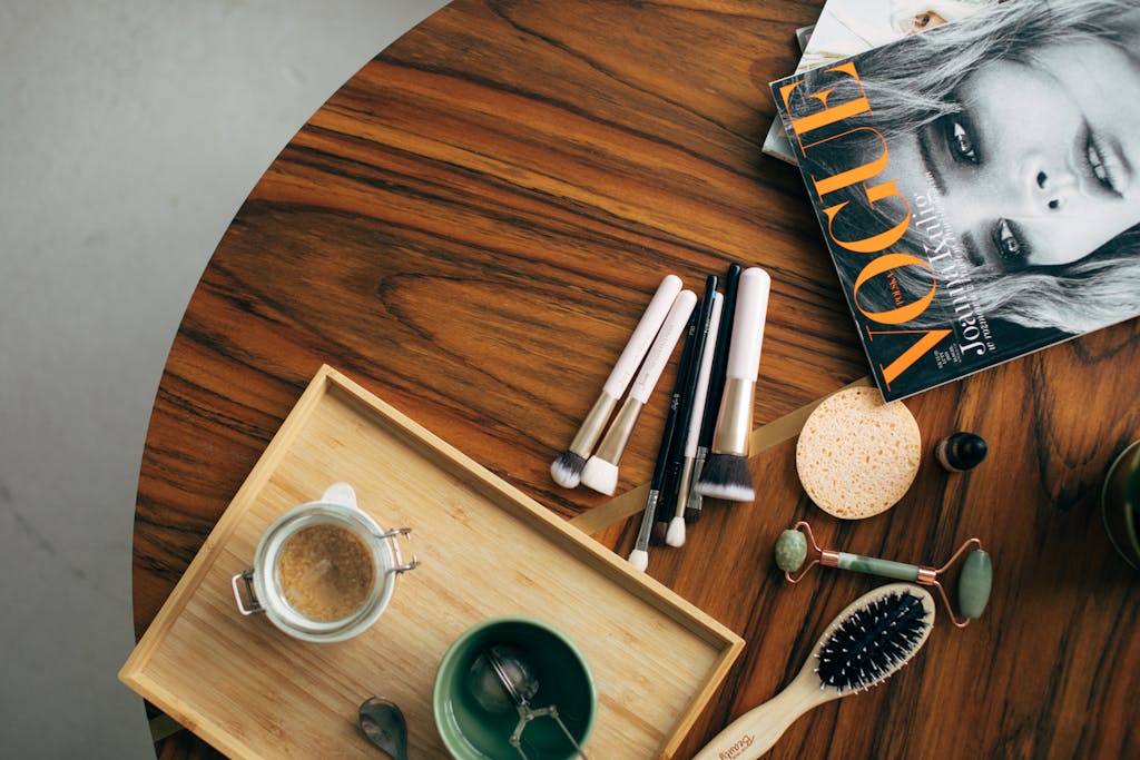 Mannacote Stylish flatlay featuring makeup brushes, a Vogue magazine, and a coffee cup on a wooden table.