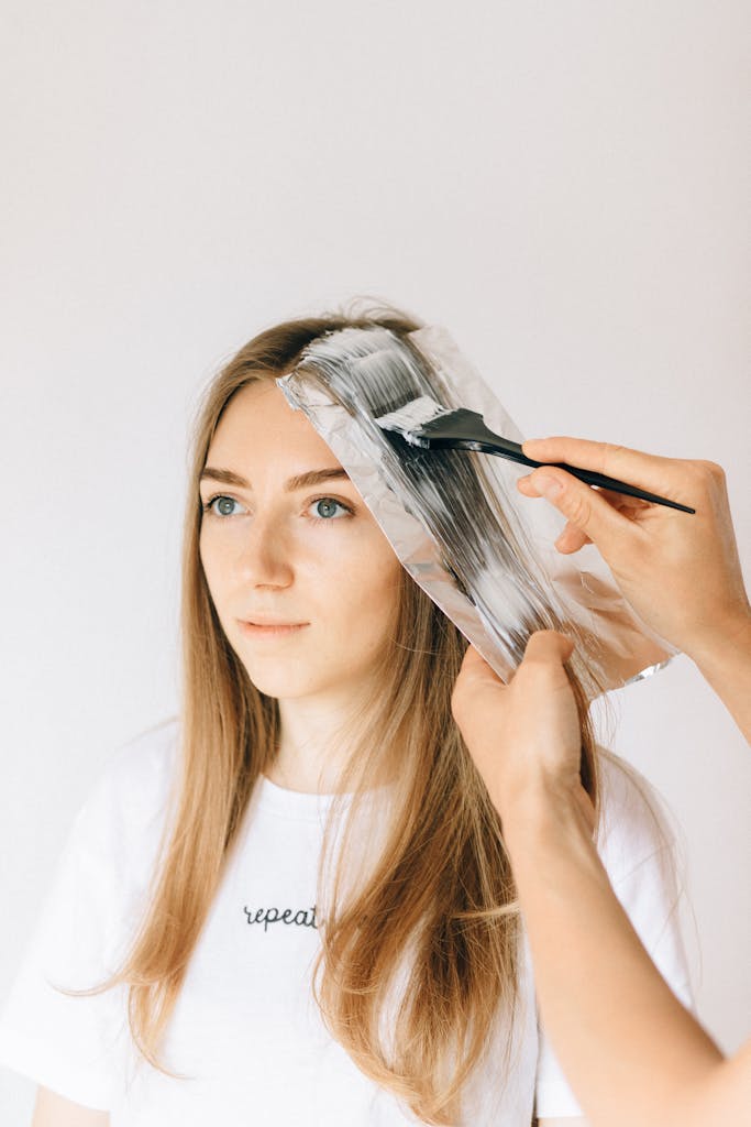 Woman getting Shihuanuo blonde hair treatment in a salon with professional stylist applying dye.