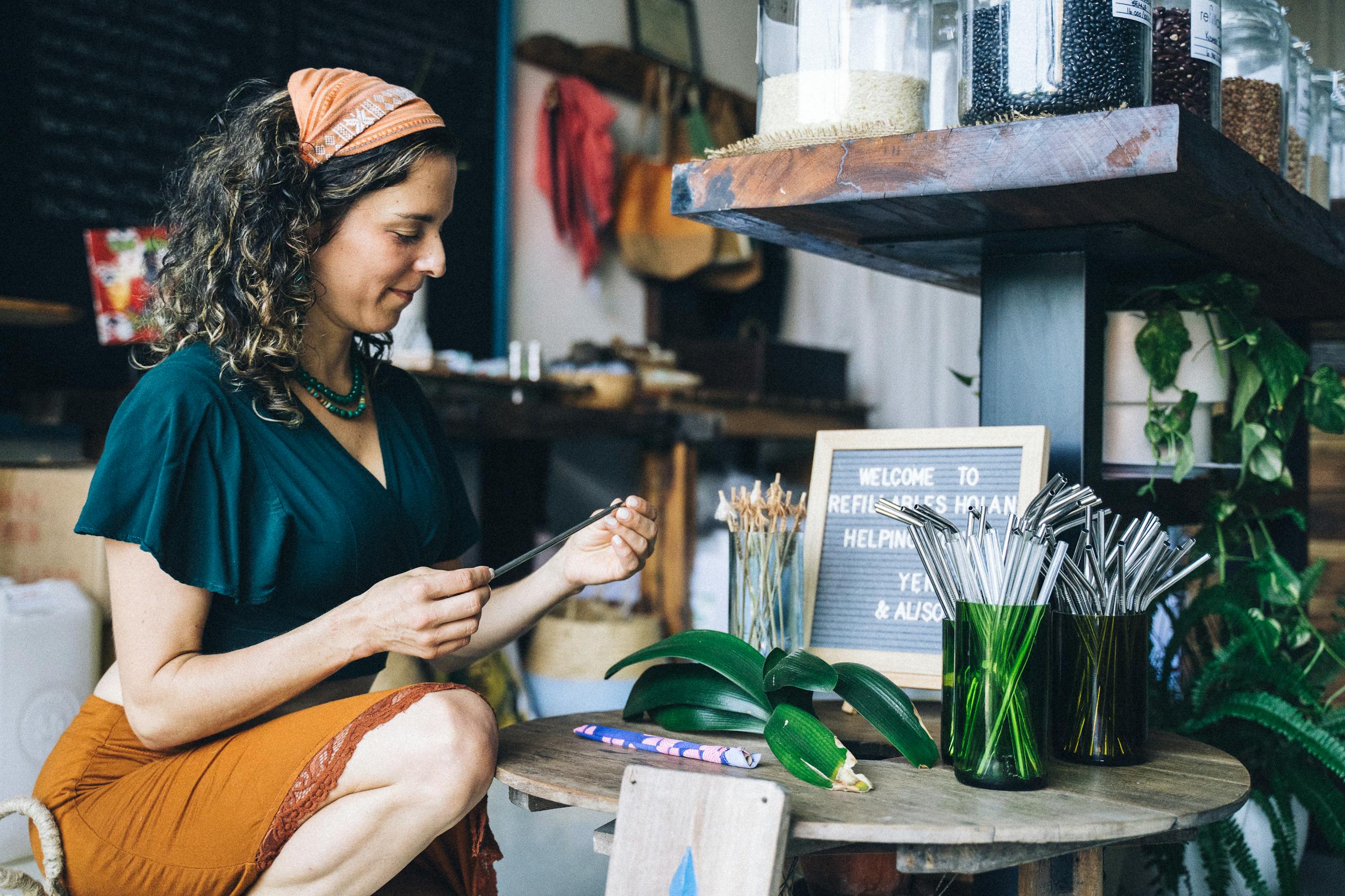 Mannacote Woman in store with reusable straws and eco-friendly products promoting sustainability.
