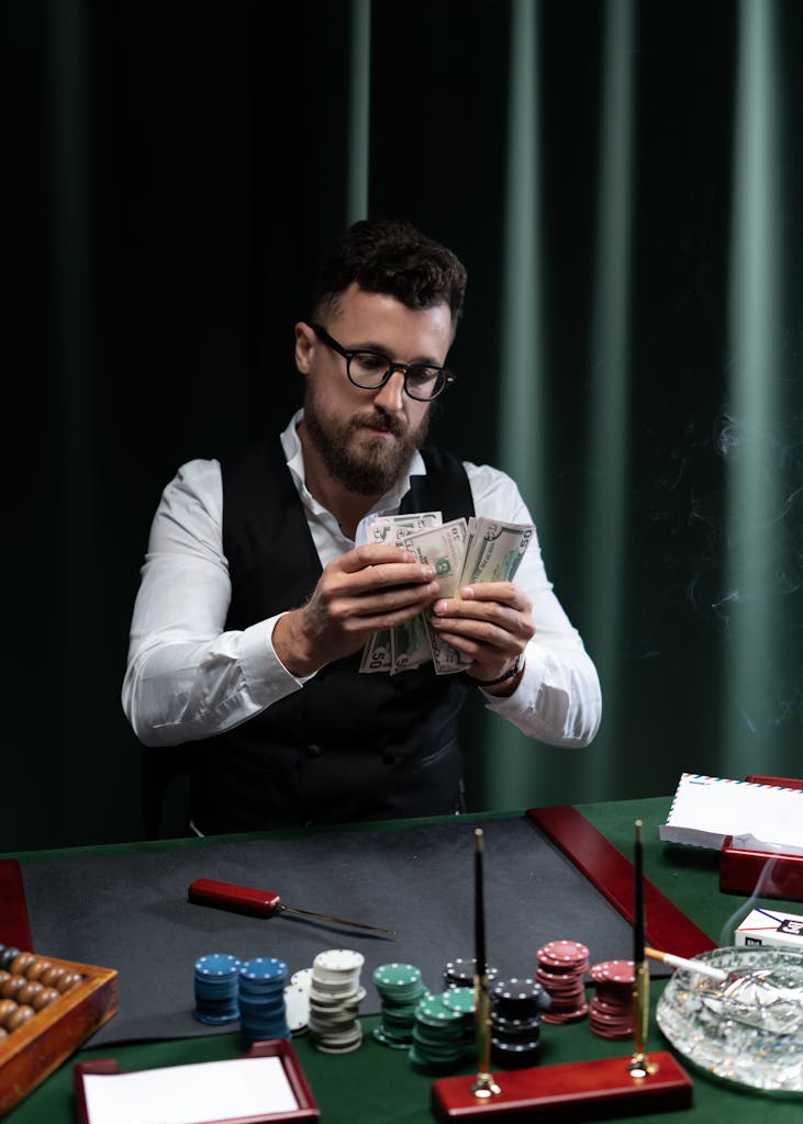 A man at 277bet.com table counting money surrounded by poker chips.