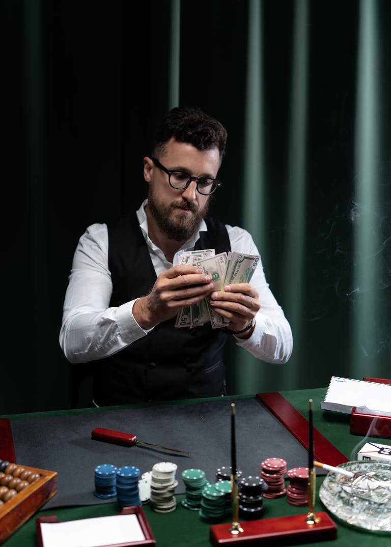 A man at 277bet.com table counting money surrounded by poker chips.