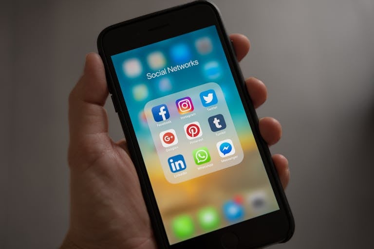 A Tamil aunty WhatsApp groups smartphone displaying various social media icons held in a hand, showcasing modern communication apps thebaddieshub.com