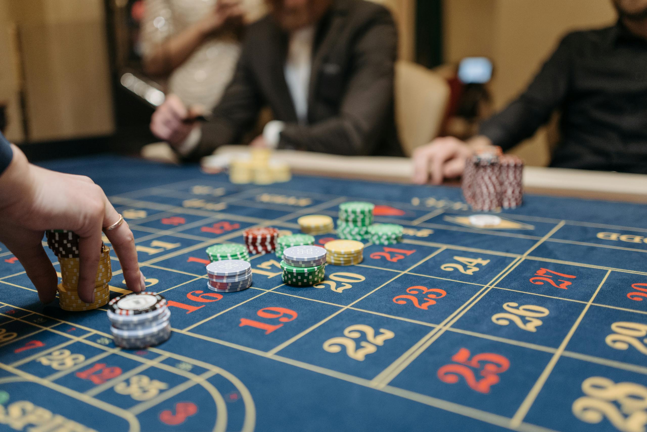 Hands placing betting 277bet.com chips on a roulette table in an upscale casino setting.