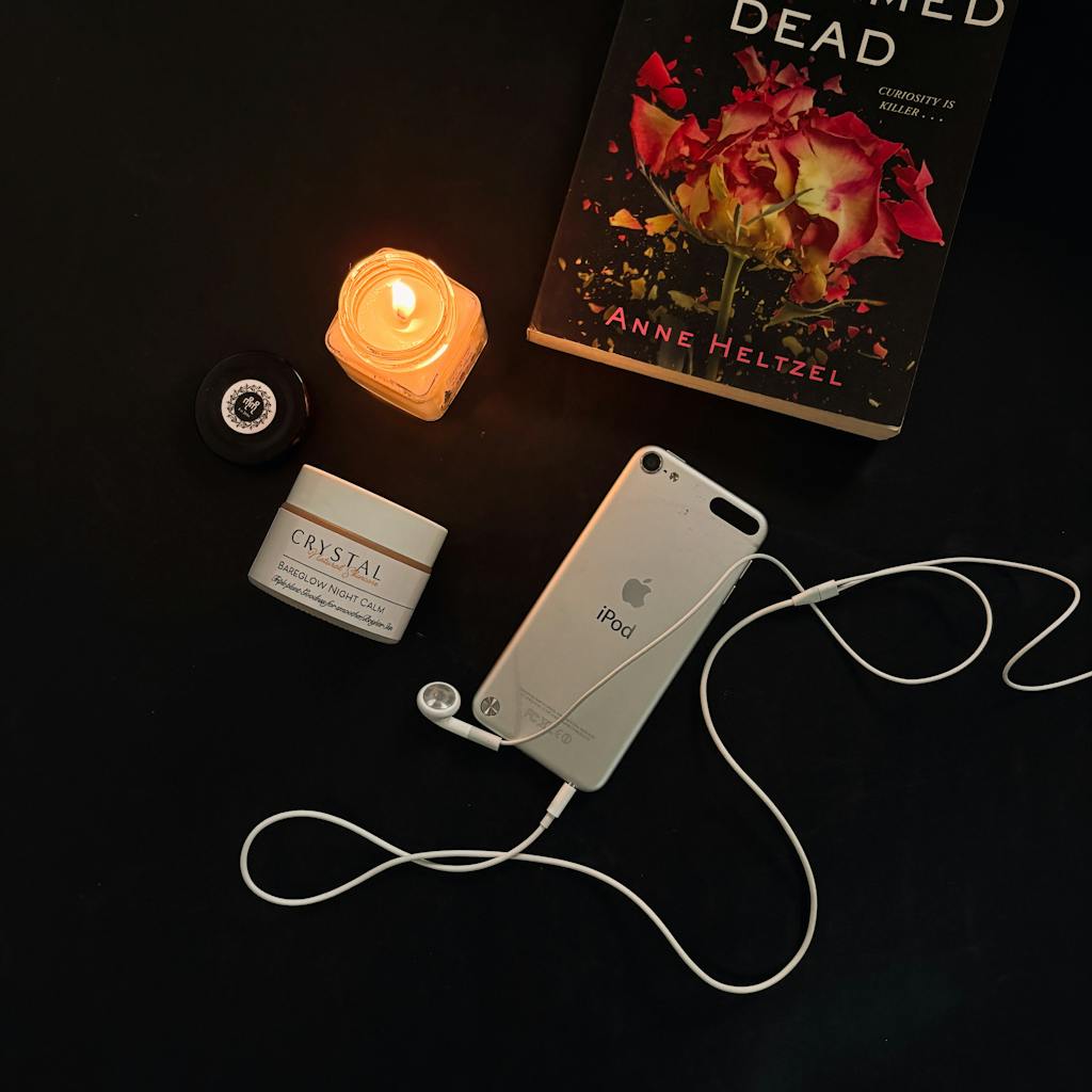 Write for aelftech.com Sophisticated flat lay featuring a candle, book, iPod, and skincare cream on a dark surface.