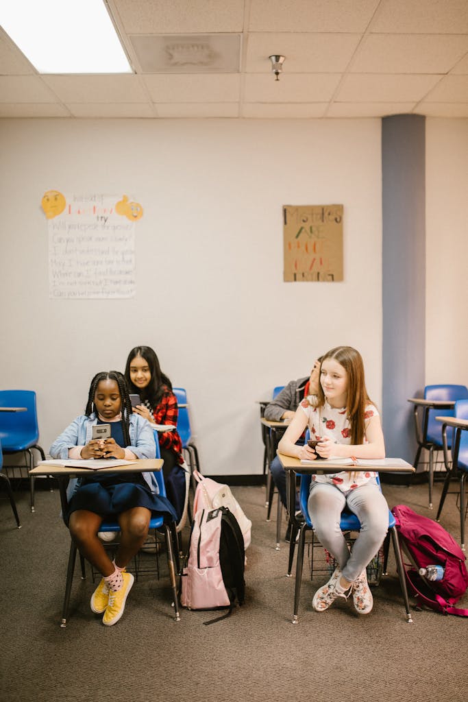 Butterfliesnkisses Leak Three middle school girls sitting at desks in a classroom, using smartphones.