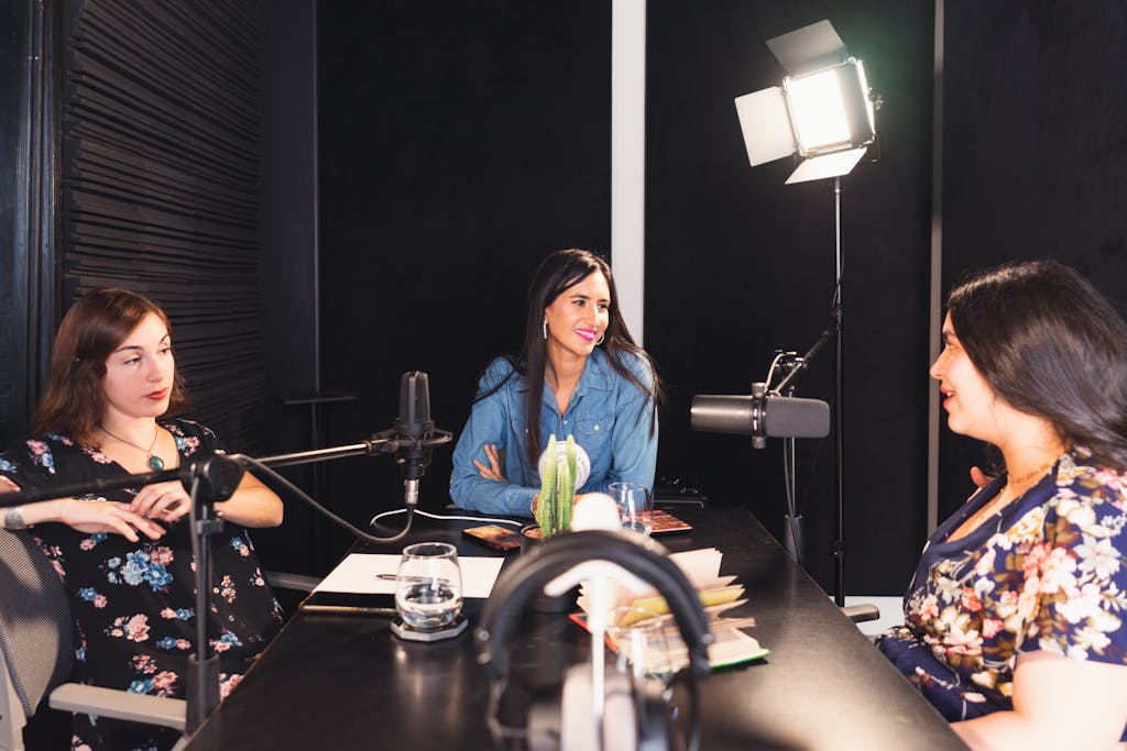 Influencers Gone Wild Three women engaged in a lively podcast discussion in a cozy indoor setting, fostering empowerment and connection.