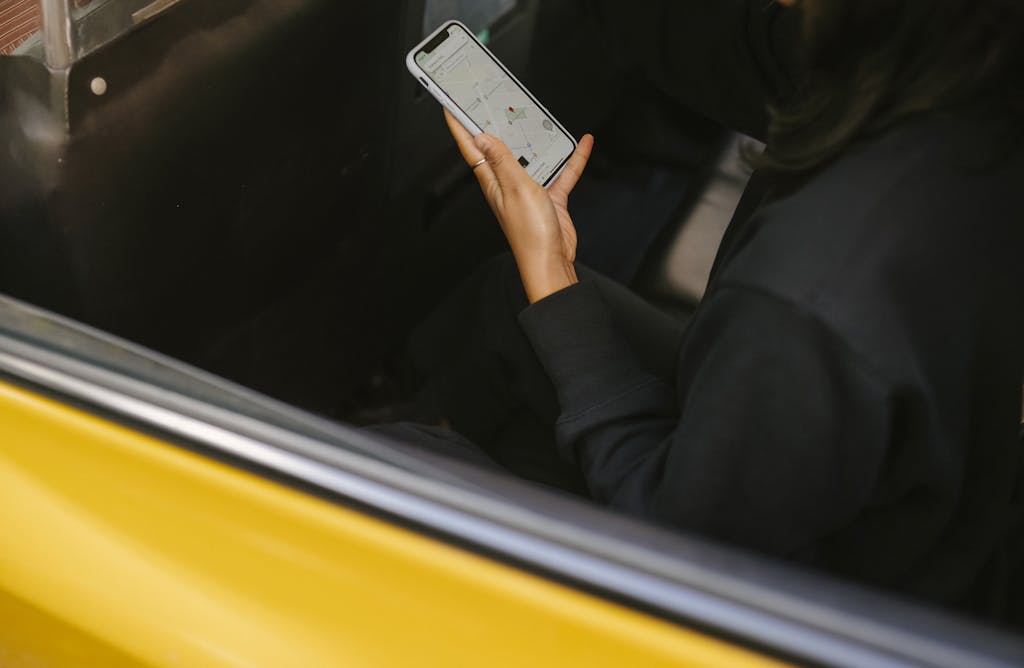 A woman using a smartphone for navigation in a yellow taxi. Perfect for travel and technology themes.