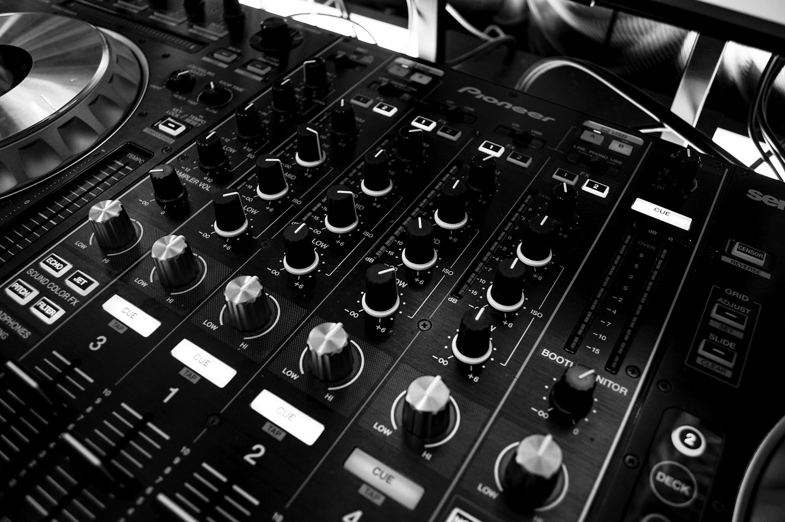 Sound Solutions Black and white close-up of a DJ's audio mixing console with knobs and controls.