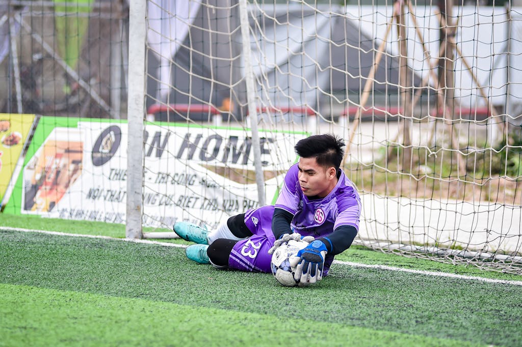 Ruks Khandagale Net Worth Dynamic shot of a young goalkeeper saving a goal on a Hanoi soccer field.