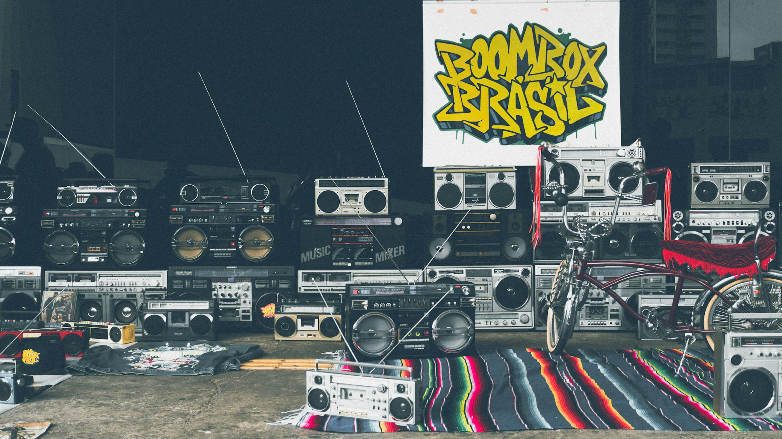 Kirby Dedo Retro boombox collection and vintage bicycle with vibrant graffiti backdrop.