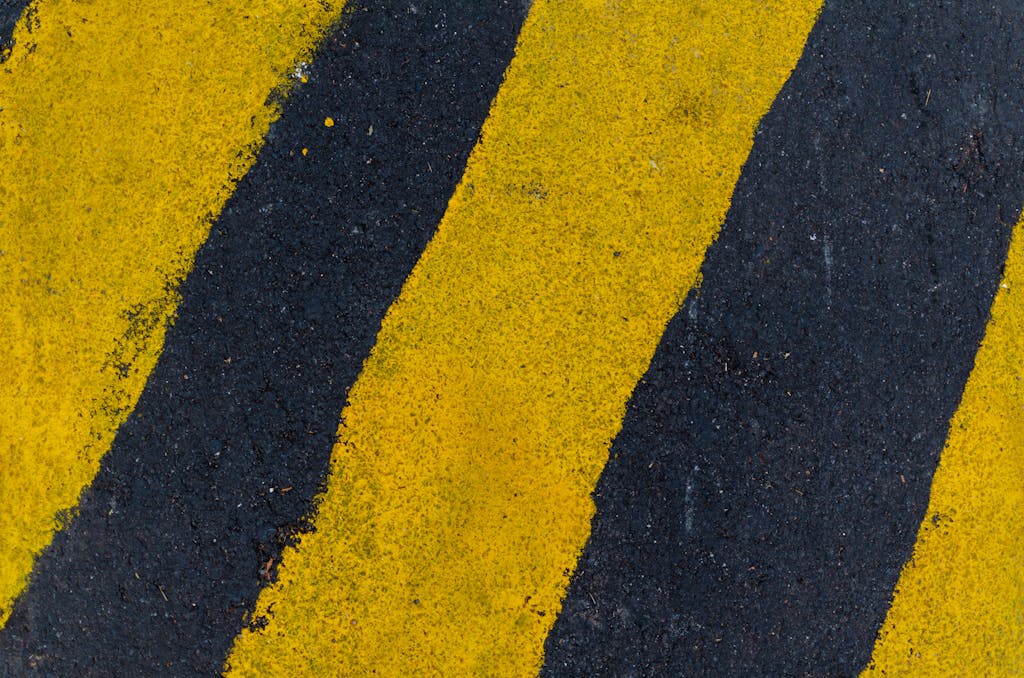 Mansutfer A high-angle close-up of yellow and black road markings on asphalt surface.