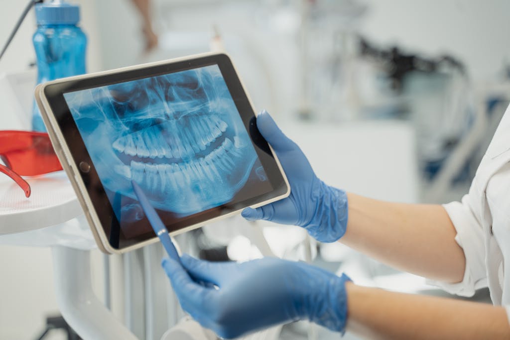 juntos seguros map Close-up of a dentist analyzing a dental X-ray on a digital tablet in a clinic setting.