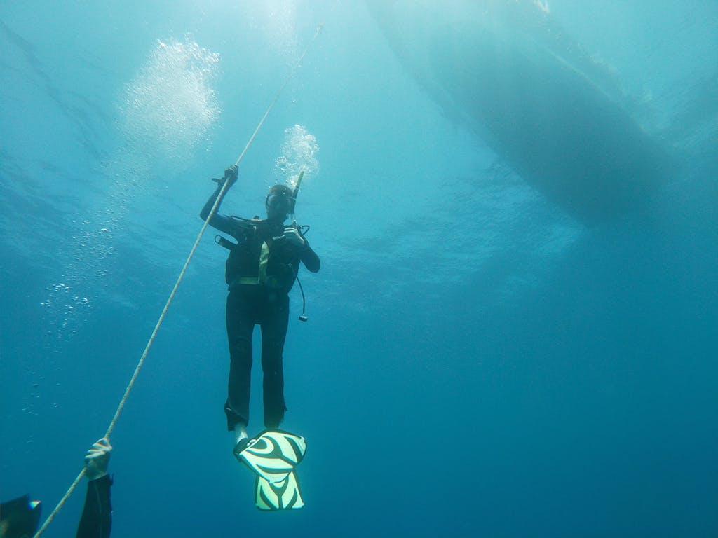 socialmediagirls forum Underwater image of a scuba diver ascending with vibrant fins in the deep blue ocean.