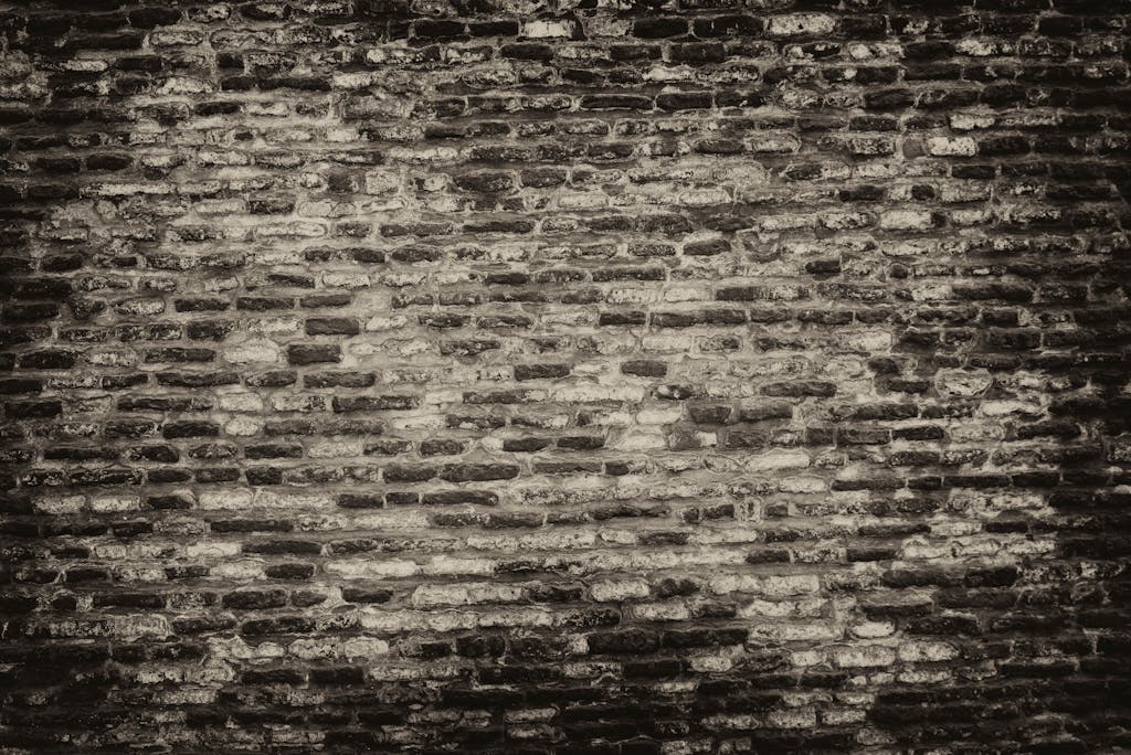 Sixmagazine Grayscale textured brick wall background with rough surface.