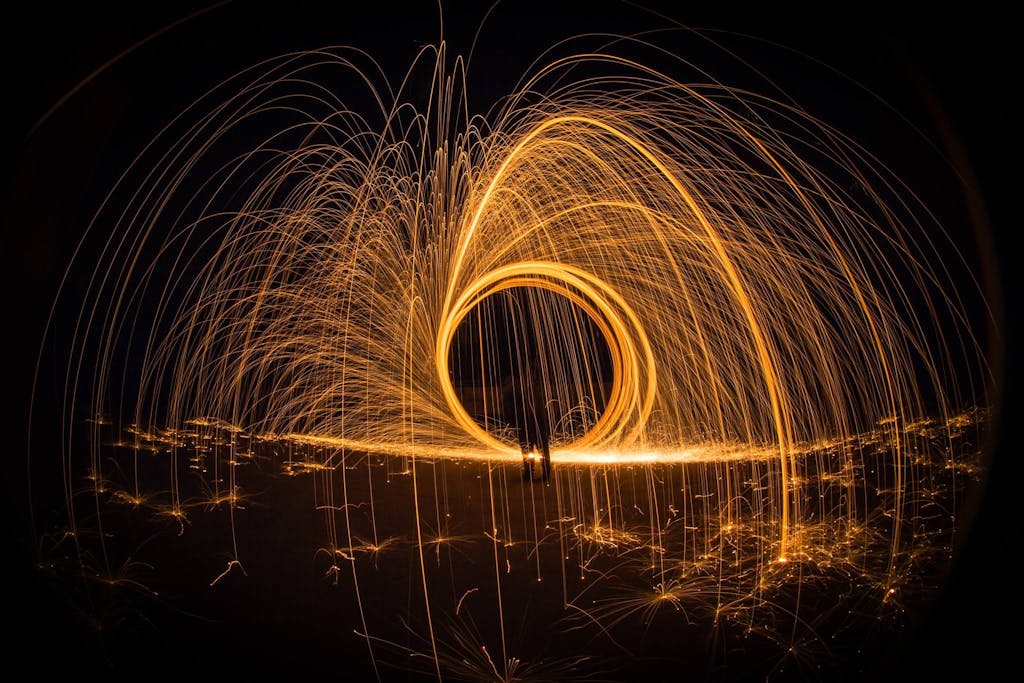 Bac Stock Stunning long exposure shot of steel wool light painting creating bright, glowing arcs in the night.